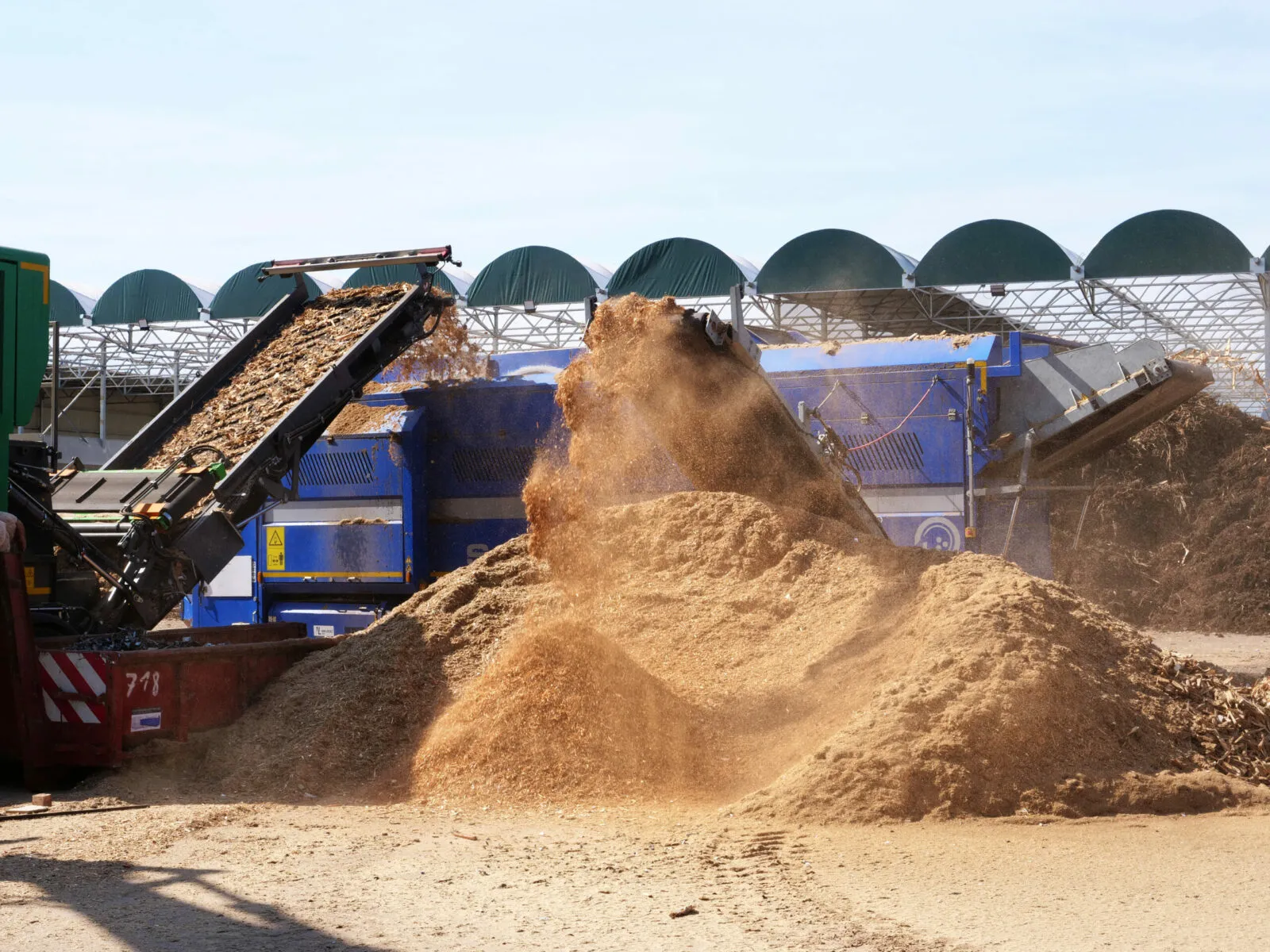 Broyeur déversant un cône de sciure sur l'aire de stockage